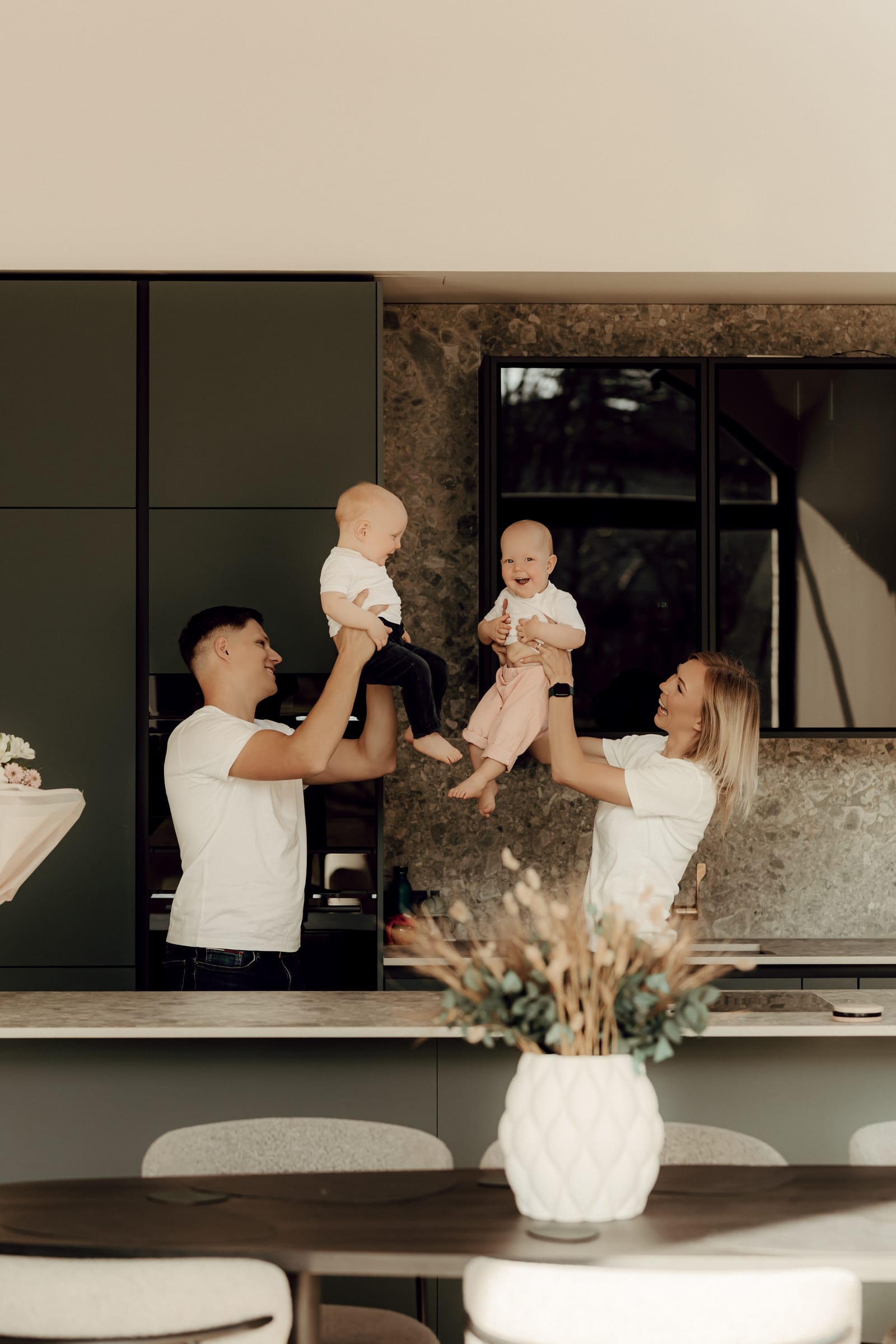 The Mealhive family in their kitchen, both parents holding up their twin babies.